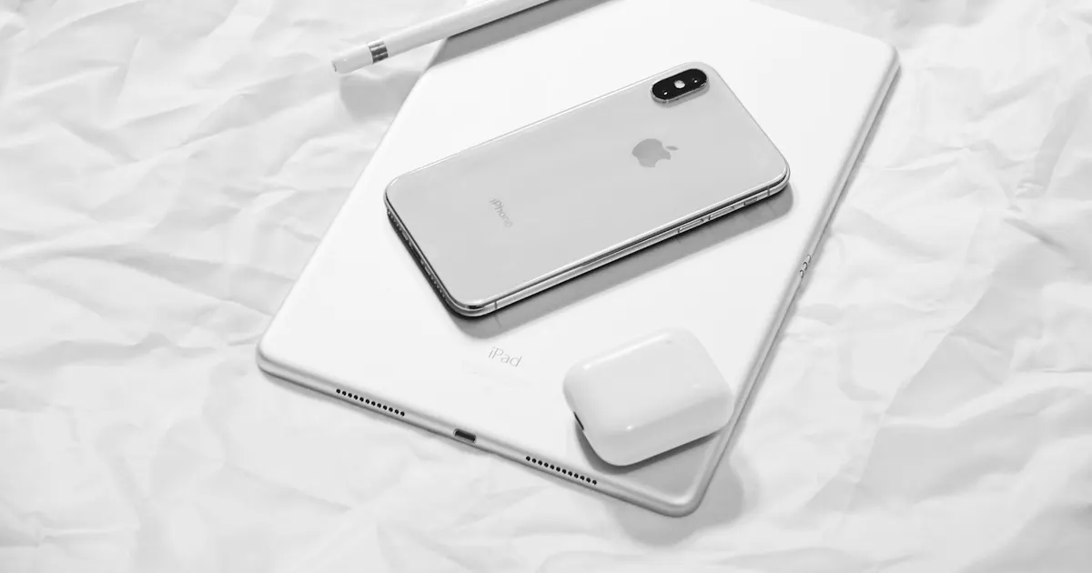 iPhone, iPad and wireless charger laid out on a white sheet